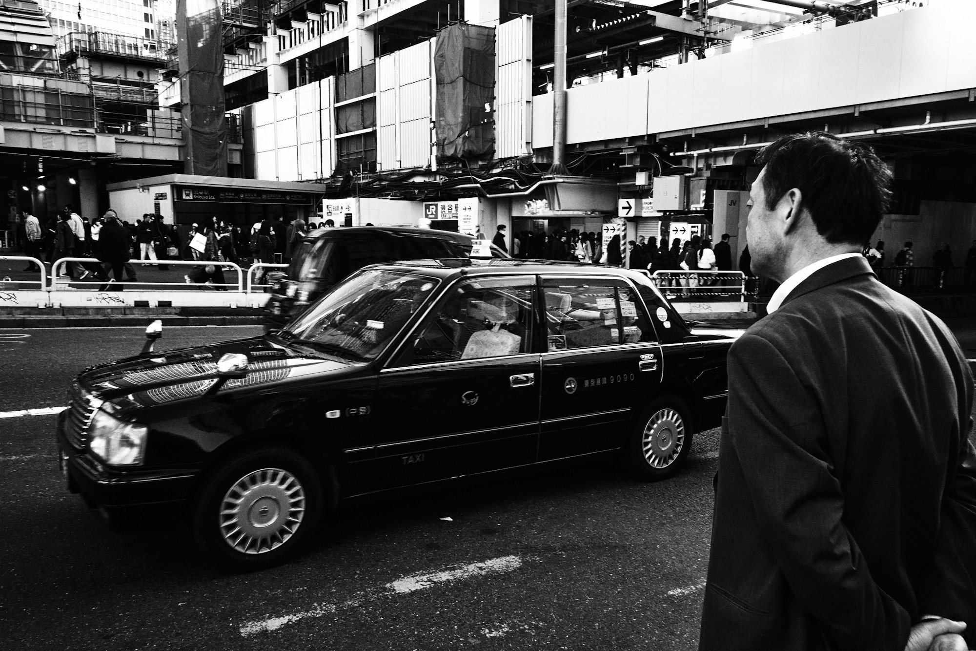 man-in-suit-waits-for-black-taxi-on-city-street-.jpg Man in suit waits for black taxi on city street.